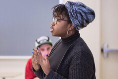 A female speaks in front of a classroom.